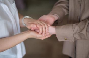 Two people holding hands in reassurance